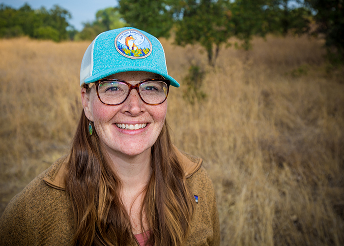 woman wearing sunglasses and a blue hat in a field