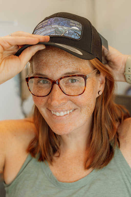 woman with glasses and red hair putting on a black hat